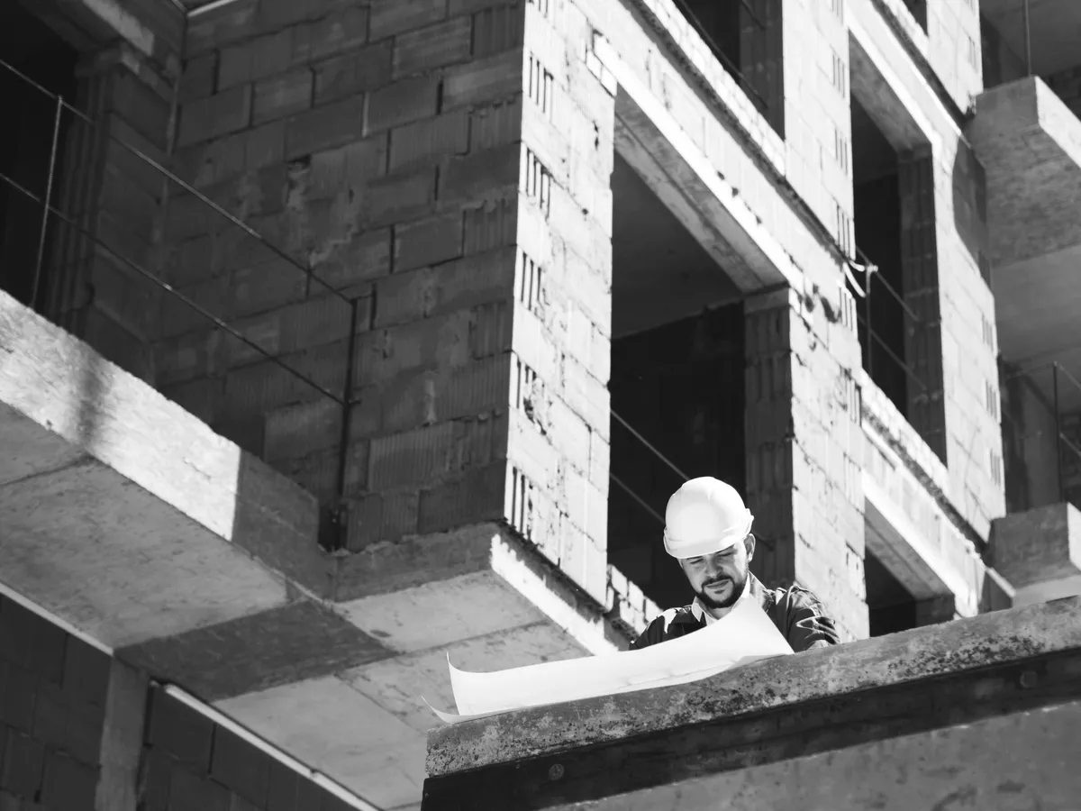 Site manager holding drawings inside a partly built structure
